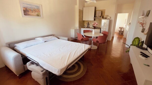 Et hotelværelse med seng, skrivebord, stol, spisebord og et tekøkken.