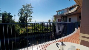En terrasse med et bord dækket til to, med udsigt over vand og en bygning.