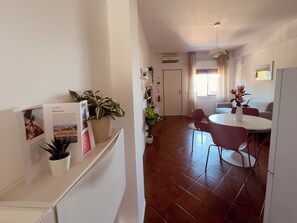 Un salon moderne comprenant un coin repas, un canapé blanc, une table basse et une plante en pot.
