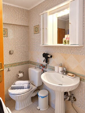 Ein Badezimmer mit Toilette, Bidet, Waschbecken und einem Spiegel darüber.