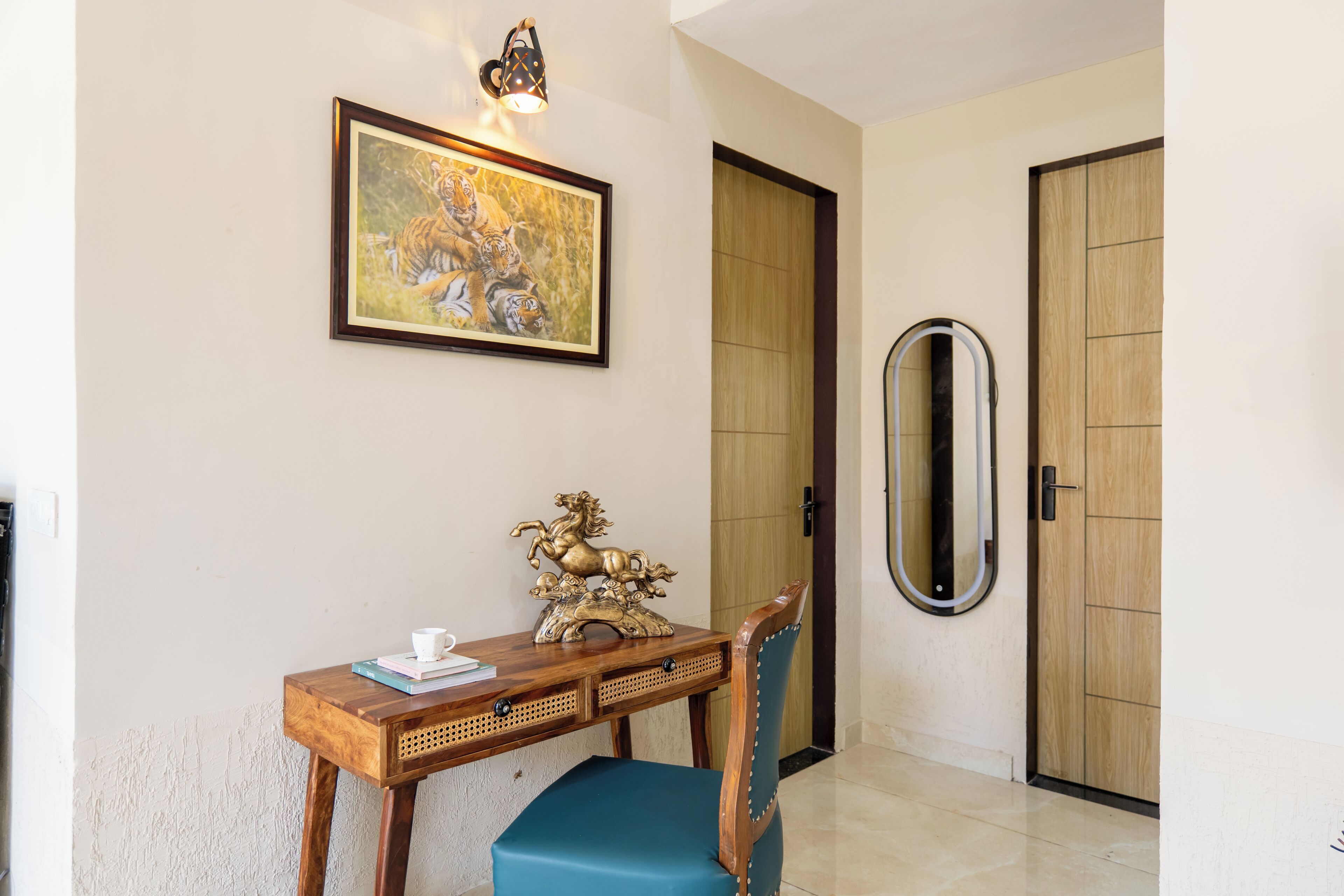 Una habitación con un escritorio de madera, una silla, un cuadro enmarcado, un espejo y una puerta.