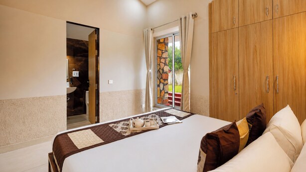 Una camera da letto con un letto, un armadio in legno e un bagno visibile tramite una porta aperta.