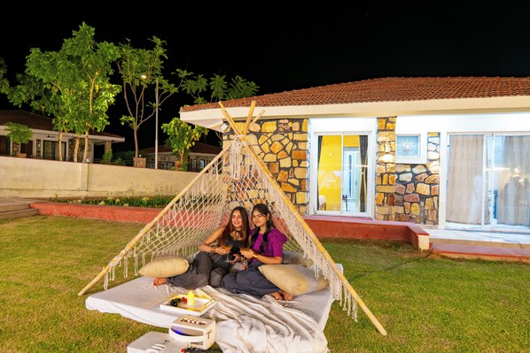 A hammock set up on a grassy lawn with a stone building in the background.