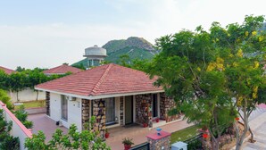 Un edificio con tetto in tegole rosse, pareti in pietra e un piccolo portico con piante in vaso.