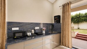 A modern kitchen with a marble countertop, a built-in microwave, a coffee maker, and a kettle.