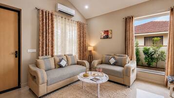 A living room with two sofas, a coffee table, and a window with curtains.