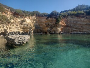 Un paisaje costero con aguas claras, acantilados rocosos y vegetación escasa.