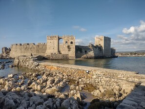 Une forteresse historique en pierre, dotée d’un fossé et bordée d’un terrain rocheux.