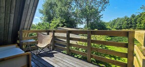 A wooden deck with a metal railing, a cushioned chair, and a small table. - Views across the fields to the sea on Langeland (Tranekær)