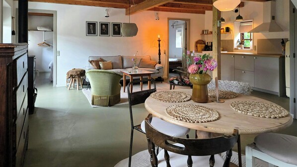 A dining area with a round table, chairs, and a vase of flowers.
