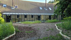 Een gebouw met een bakstenen gevel, grote ramen en een grindhof.