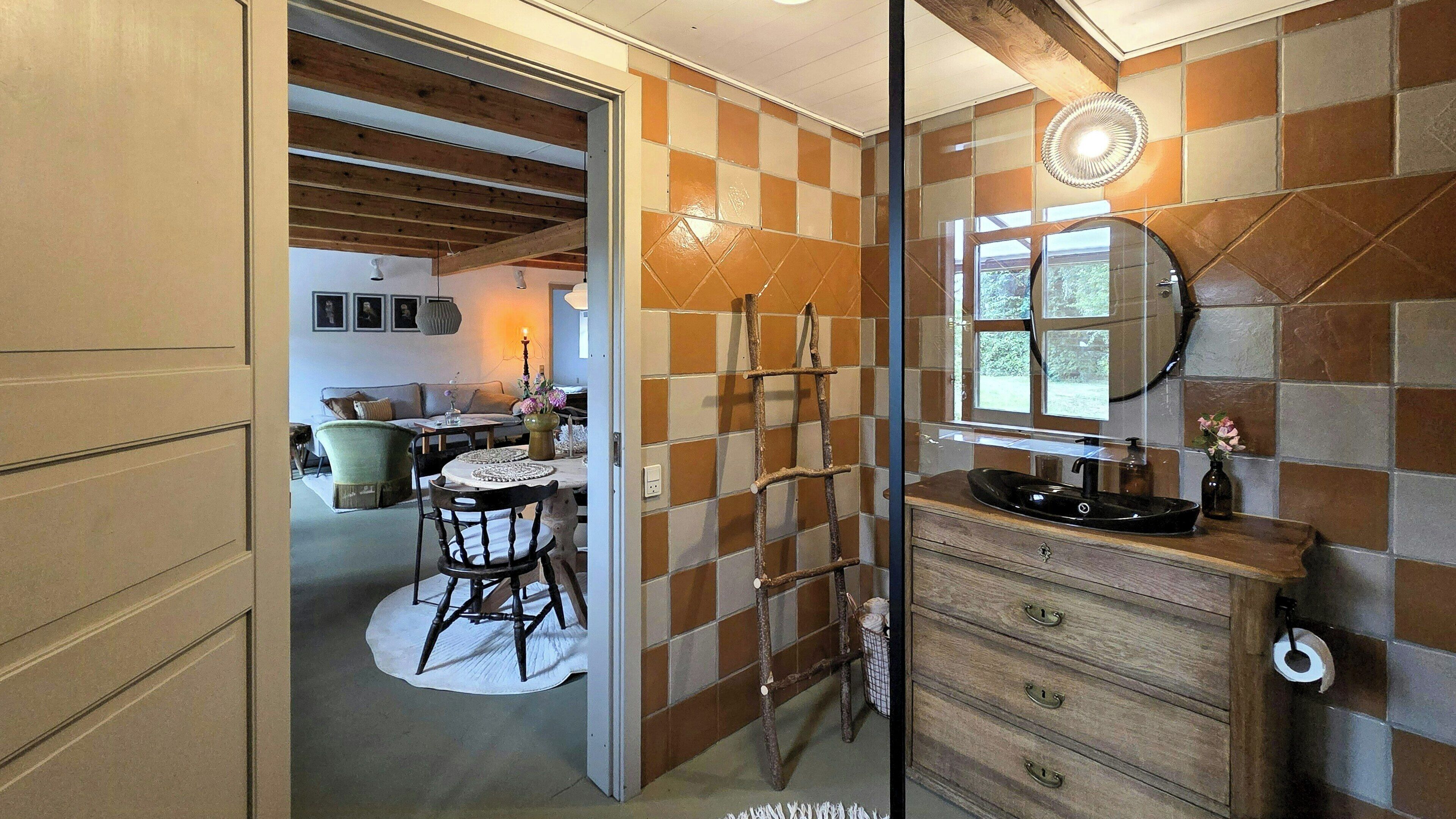 Un bagno con un mobile vanitario in legno, uno specchio e una finestra.