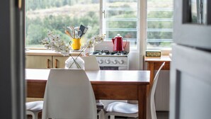 Una cocina con una mesa de comedor, sillas, estufa y ventana con vista a la vegetación.