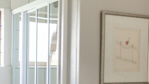Una habitación con una puerta que da a un balcón, un cuadro en la pared y suelo de baldosas.