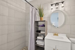 Un bany modern amb dutxa, un lavabo amb rentapèns i un mirall.
