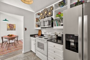 Eine moderne Küche mit weißen Schränken, einem Edelstahlkühlschrank, einer Mikrowelle und einem Herd.