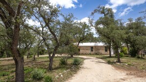 A rural property with a dirt path leading to a stone building, surrounded by trees.