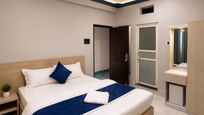 A modern hotel room with a large bed, bedside tables, a wardrobe, and a bathroom with a glass door. - The SkyLine Hotel (Bhedetar)