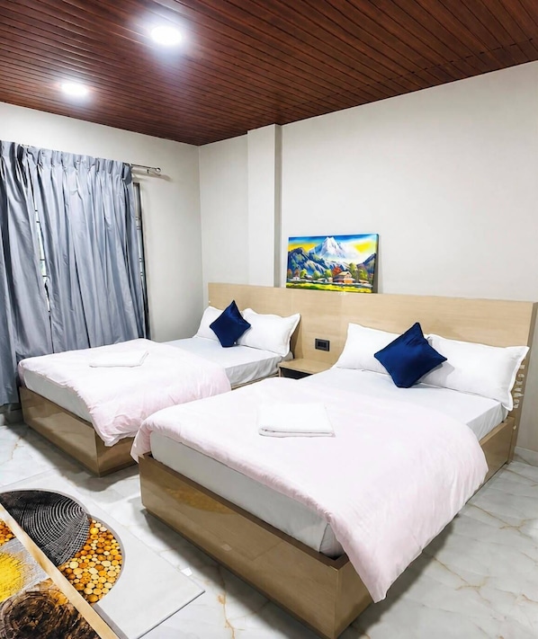 Habitación de hotel con dos camas, un cuadro en la pared y una ventana con cortinas.