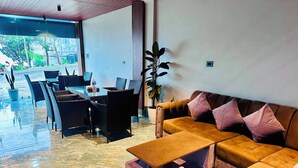 A modern interior with a sofa, chairs, a table, and a potted plant. - The SkyLine Hotel (Bhedetar)