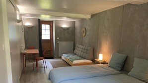 A bedroom with a bed, bedside table, lamp, chair, and a small table with a chair.