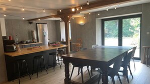 A modern kitchen with a central island, bar stools, and a dining table with chairs.