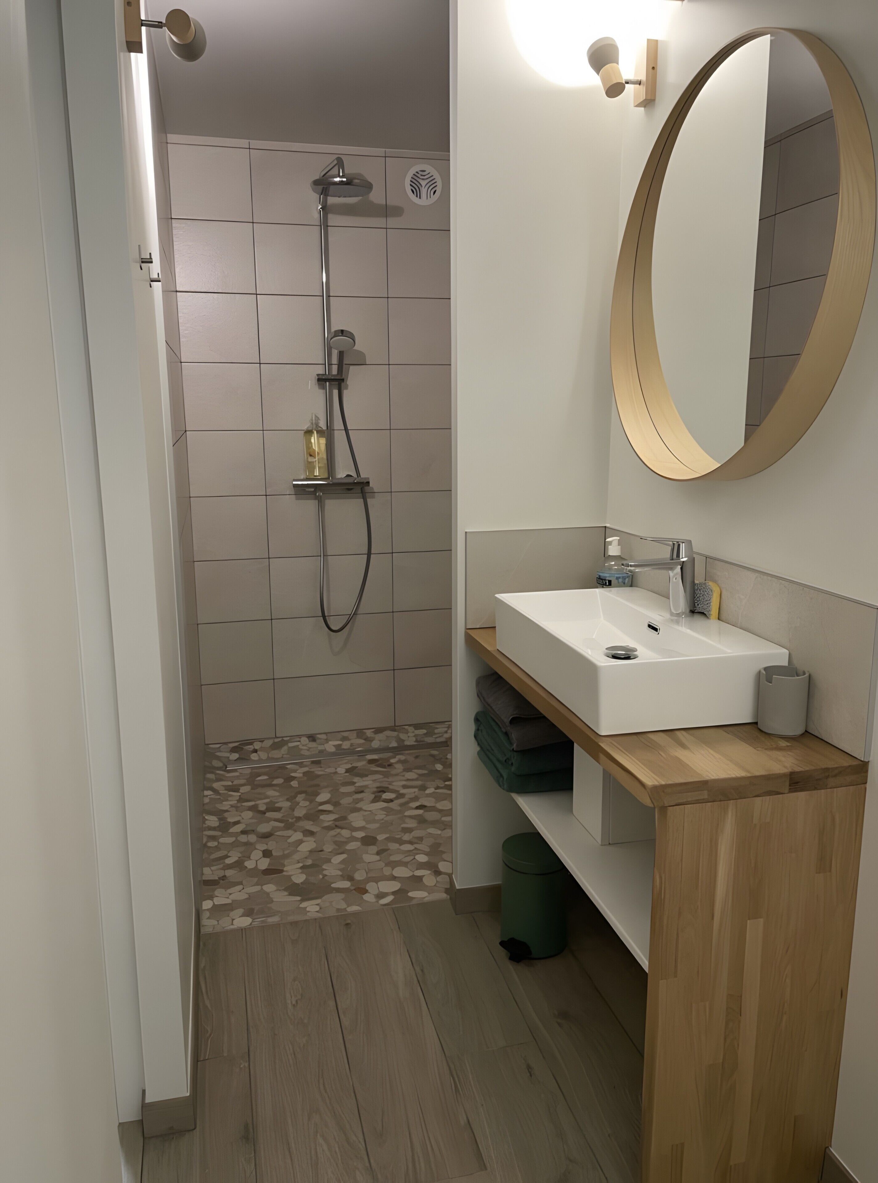 A bathroom with a shower, a sink, a mirror, and a toilet.