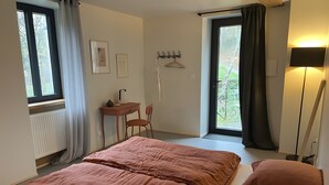 A bedroom with a bed, a desk, a chair, and a window with curtains.