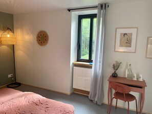 Makuuhuone, jossa on sänky, työpöytä, tuoli, ikkuna verhoilla, patteri ja seinäkoristeita.