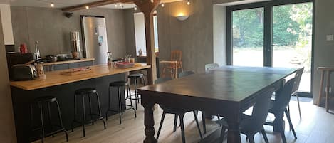 A modern kitchen with a central island, bar stools, and a dining table with chairs.