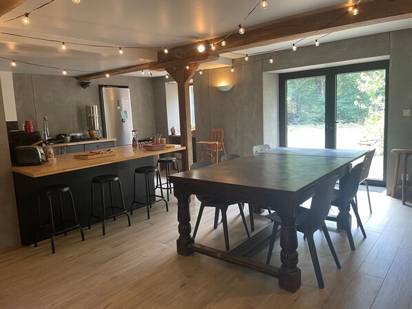 A modern kitchen with a central island, bar stools, and a dining table with chairs.