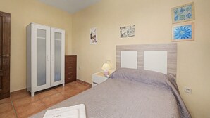Un dormitorio con una cama, un armario, una mesita de noche y una lámpara.