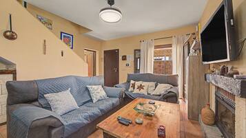 A living room with two sofas, a coffee table, a fireplace, and a television.