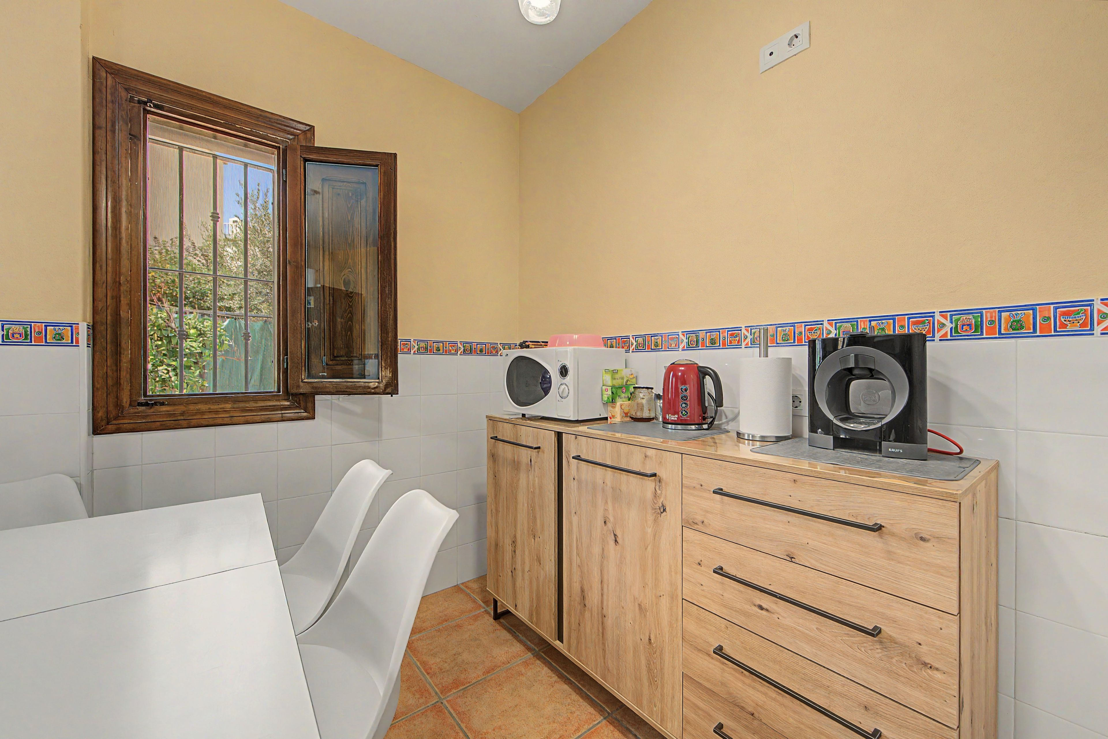 A compact kitchen with a wooden cabinet, a coffee maker, and a kettle.