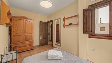 A bedroom with a bed, a wardrobe, a mirror, and a window.