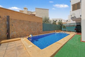 Una piscina con un muro de piedra y una valla de metal.