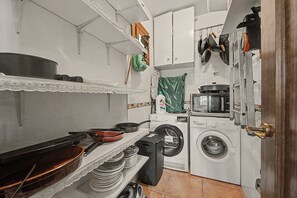 Una cocina funcional con lavadora, estufa y diversos utensilios.