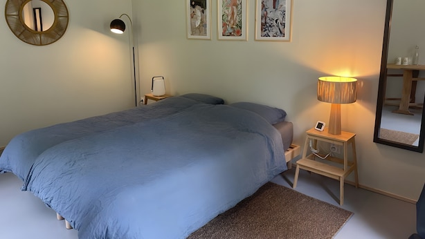 Ein Schlafzimmer mit Bett, Nachttischlampen, einem Nachttisch und Wandbildern.