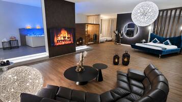 A modern living room with a fireplace, leather sofas, a round coffee table, and a blue sofa.