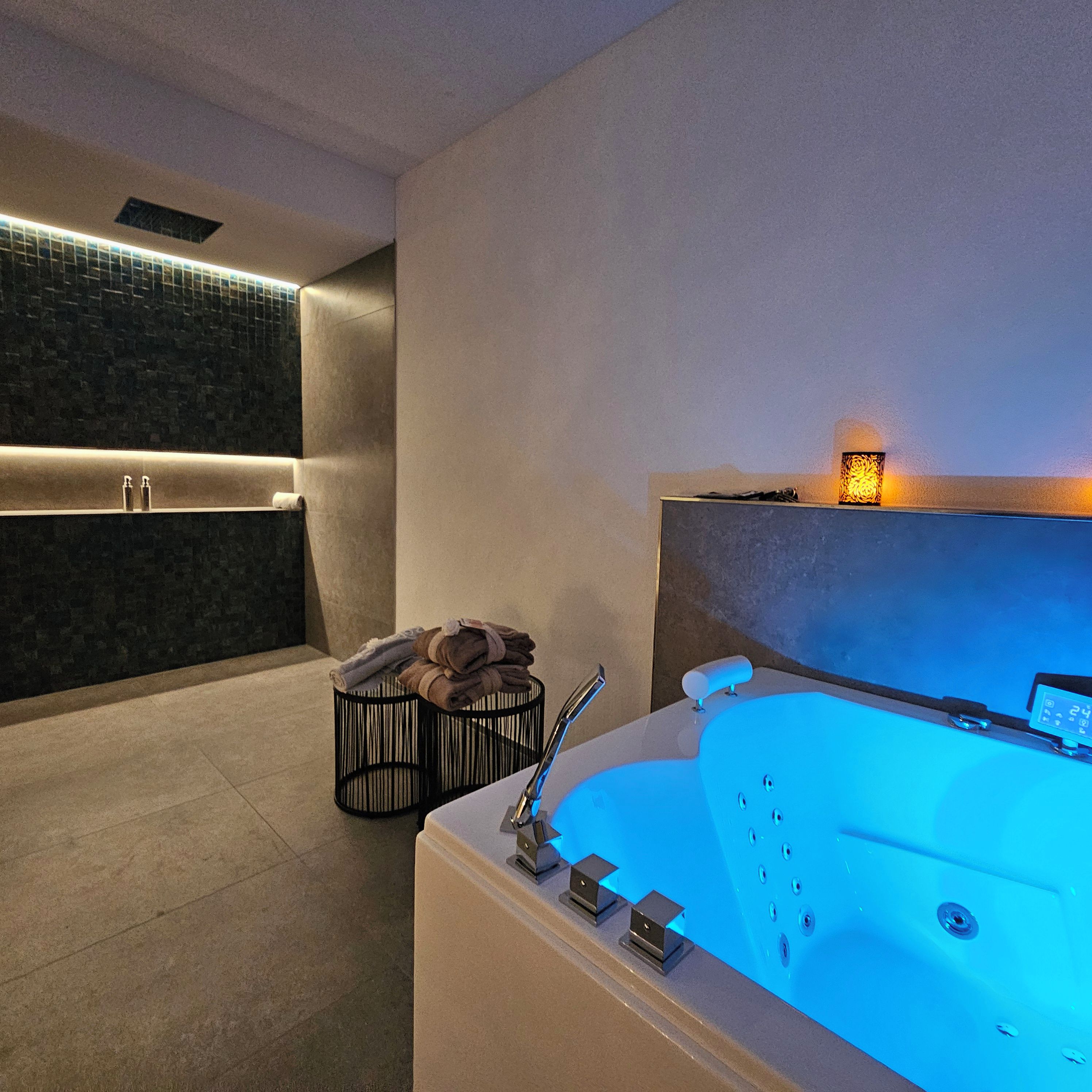 A modern bathroom with a large bathtub, a towel rack, and a wall-mounted light fixture.