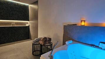 A modern bathroom with a large bathtub, a towel rack, and a wall-mounted light fixture.