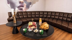 Una sala moderna con un sofá de cuero, una mesa de centro redonda negra y una composición decorativa que incluye un jarrón, aperitivos y una botella.