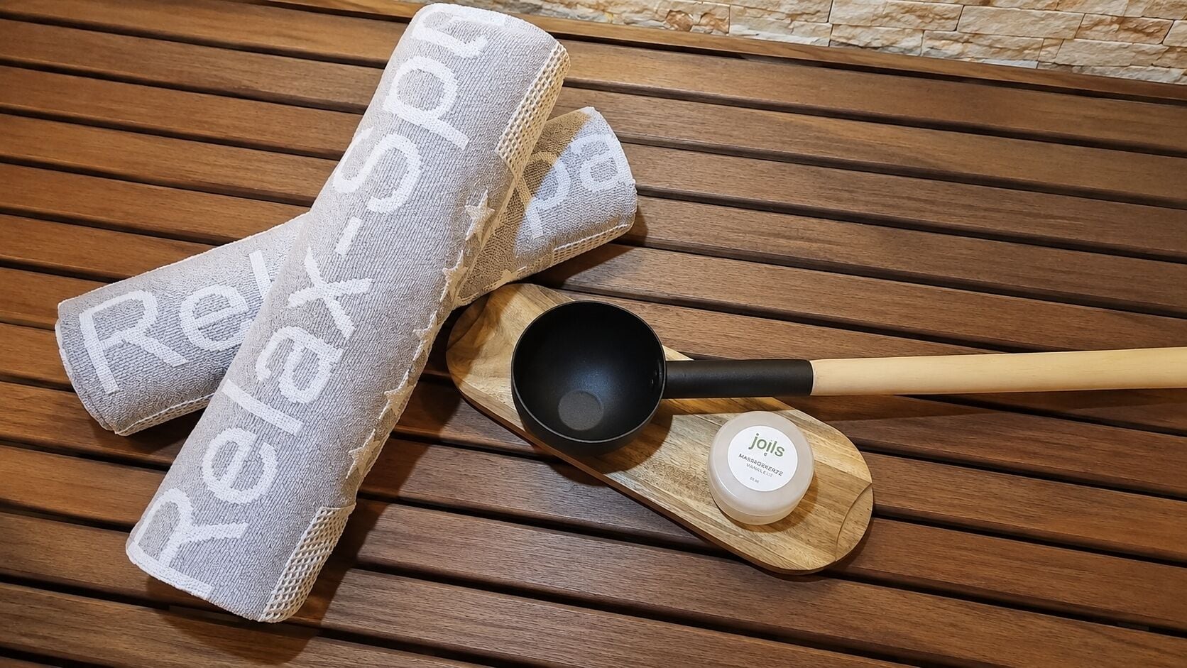 Une table en bois sur laquelle se trouvent un bol noir, une cuillère en bois et un récipient contenant des « joils », le tout posé sur un plateau en bois.