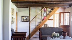 A room with a wooden staircase, a grey sofa, and a white chair.