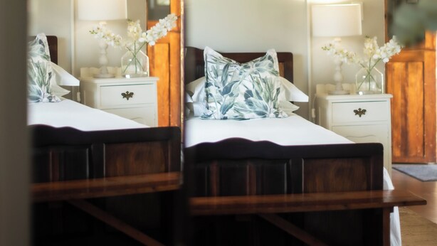 A bedroom with a bed, bedside tables, and a mirror reflecting the room.