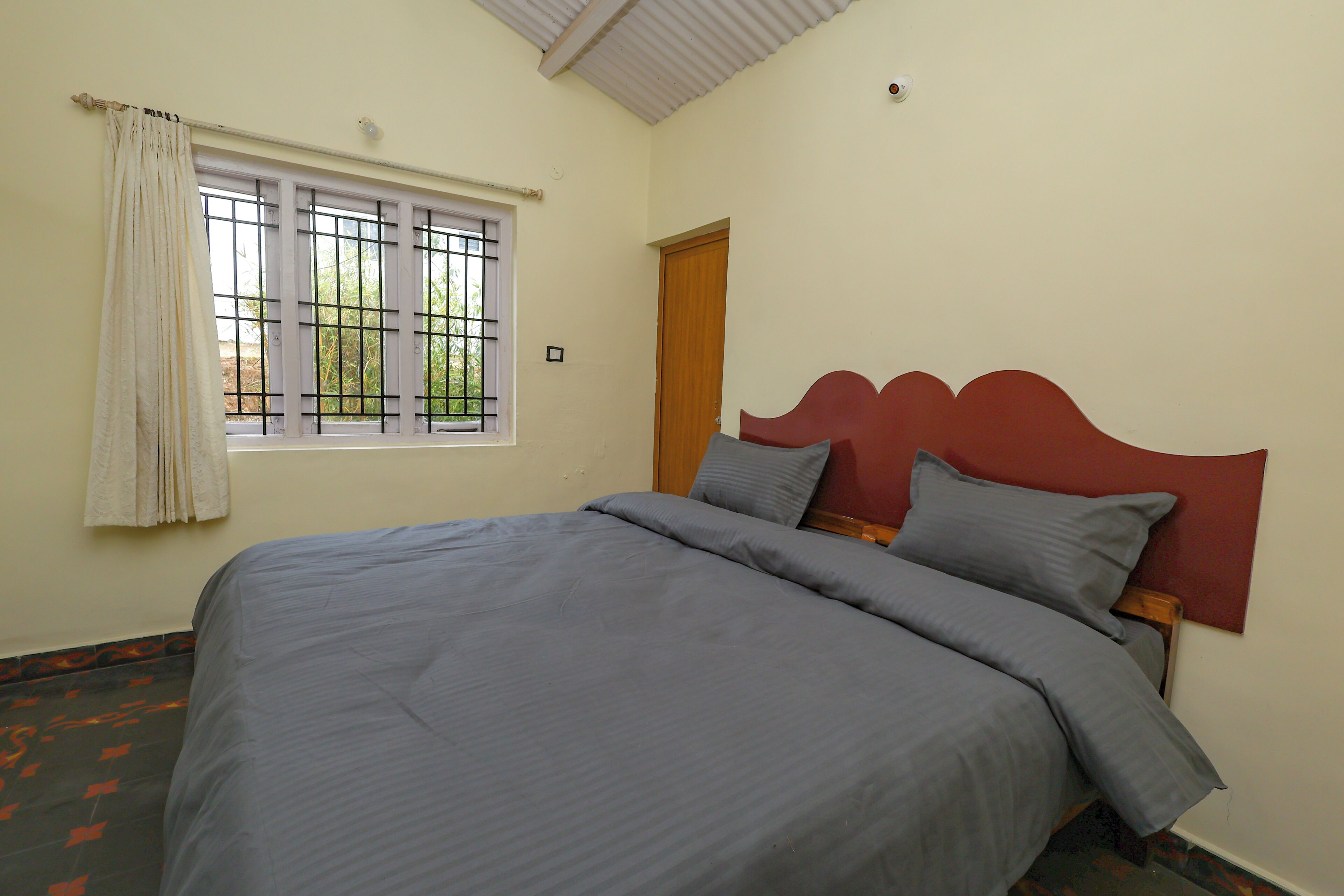 A room with a bed, a window with a view, and a door.