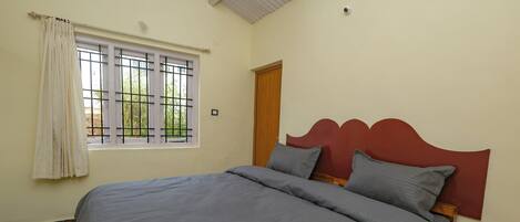 A room with a bed, a window with a view, and a door.