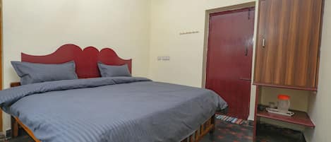 Une chambre à coucher avec un lit, une armoire, une petite étagère et une porte.