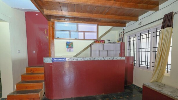 A reception area with a reception desk, a staircase, and a window with curtains. - Mistora Valley (Ooty)