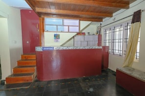 A reception area with a reception desk, a staircase, and a window with curtains. - Mistora Valley (Ooty)